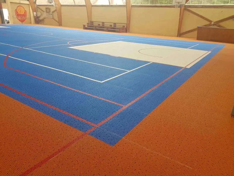 Terrain de basket intérieur en dalles Flexipads bleues et orange avec le tracé des lignes de jeu
